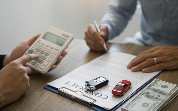 Foto seção média de um vendedor de automóveis a assinar um contrato com um cliente no escritório