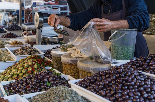 Seção média de um vendedor embalando azeitonas em sacos em uma barraca de mercado