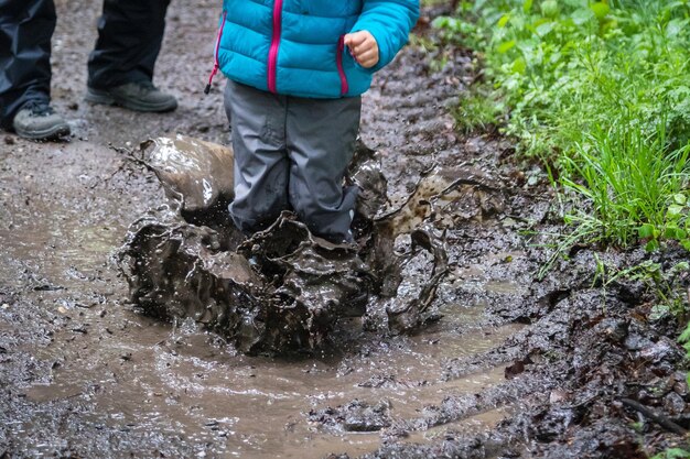 Seção média de uma criança salpicando na lama