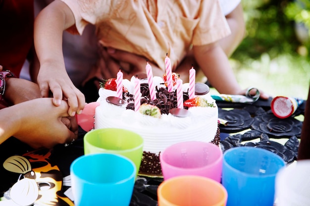 Foto seção média de uma família cortando bolo de aniversário na mesa no quintal