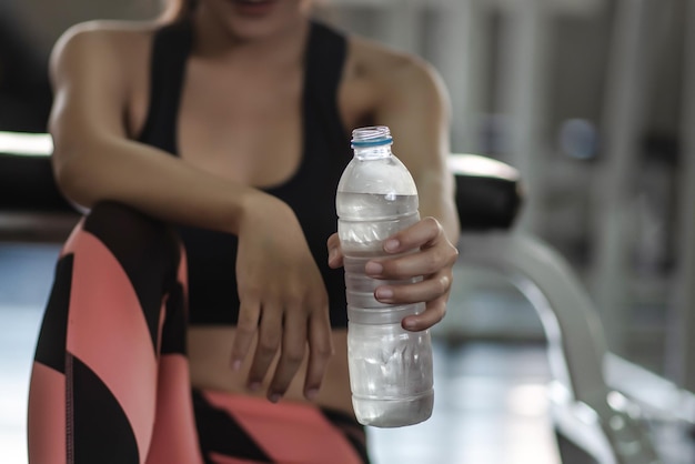 Foto seção média de uma jovem segurando uma garrafa de água no ginásio