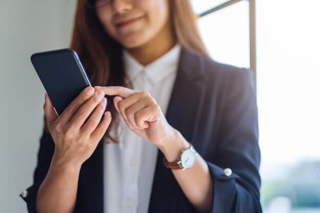 Foto seção média de uma mulher de negócios usando o telefone enquanto está de pé no escritório