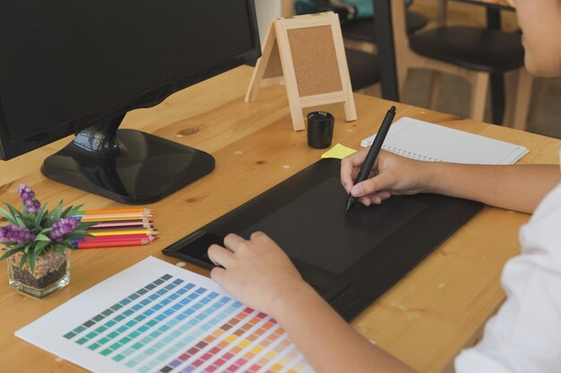 Seção média de uma mulher de negócios usando um tablet gráfico com caneta digitalizada por computador na mesa