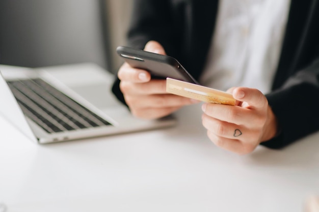 Seção média de uma mulher de negócios usando um telefone móvel enquanto segura um cartão de crédito