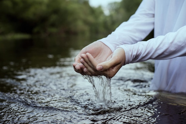 Seção média de uma mulher de pé com as mãos em copos no lago