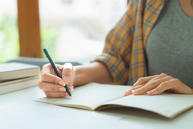 Seção média de uma mulher escrevendo em um livro