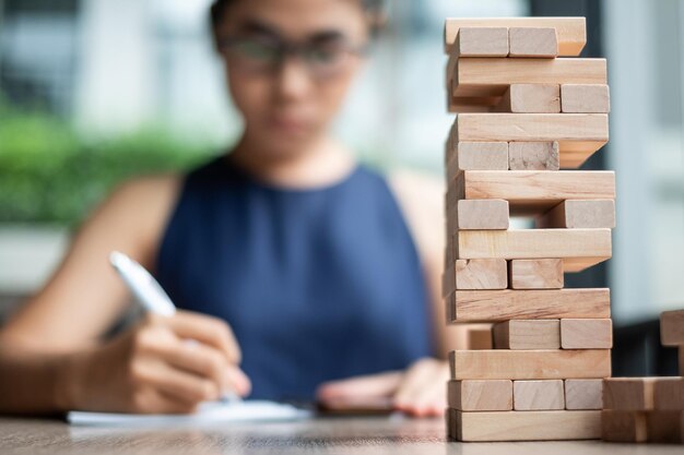 Foto seção média de uma mulher escrevendo por jogo de remoção de blocos na mesa