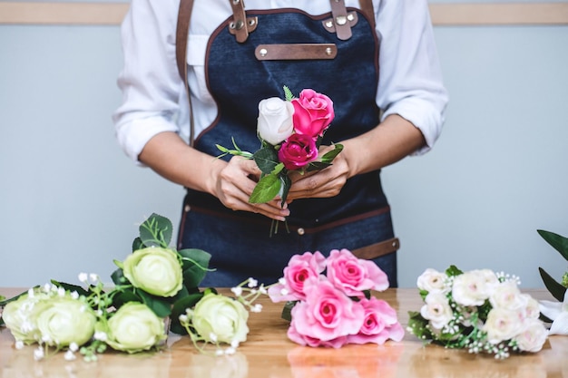 Seção média de uma mulher fazendo um buquê de rosas