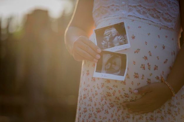Foto seção média de uma mulher grávida segurando ultra-som na barriga