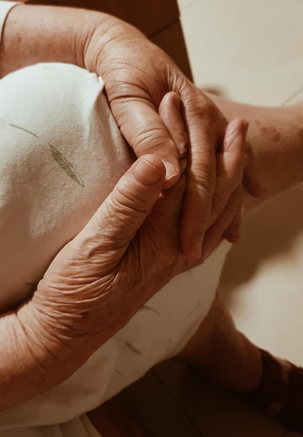 Seção média de uma mulher idosa com as pernas cruzadas no joelho sentada dentro de casa
