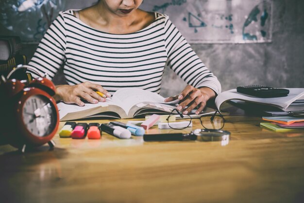 Seção média de uma mulher lendo um livro sentada à mesa