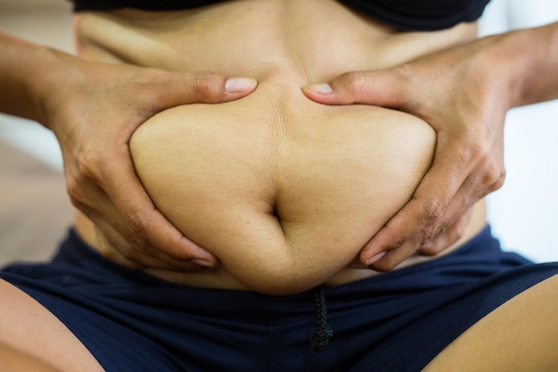 Foto seção média de uma mulher segurando a barriga contra um fundo branco