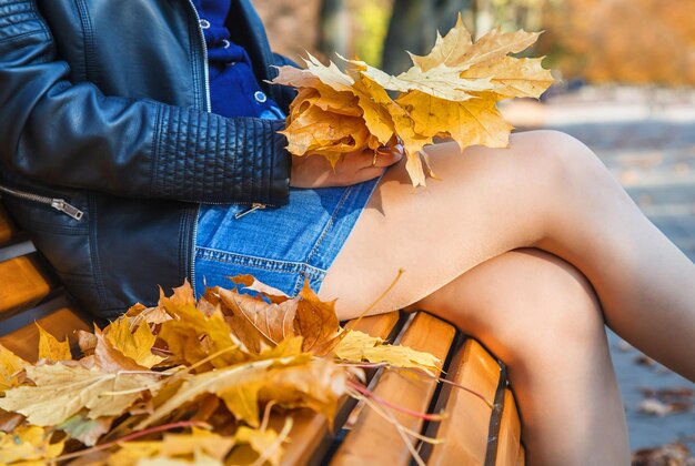 Seção média de uma mulher sentada em um banco durante o outono