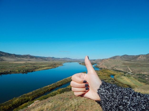 Foto seção média de uma pessoa na montanha contra um céu azul claro