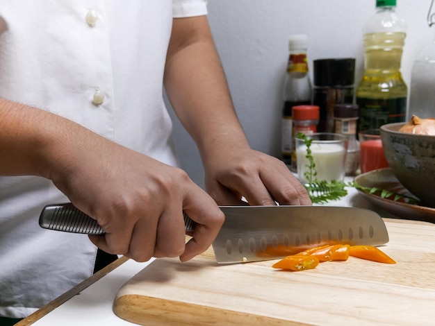 Seção média de uma pessoa preparando alimentos em uma tábua de cortar