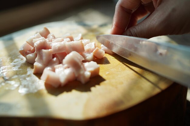 Seção média de uma pessoa preparando alimentos em uma tábua de cortar