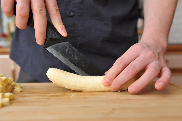 Seção média de uma pessoa preparando alimentos em uma tábua de cortar