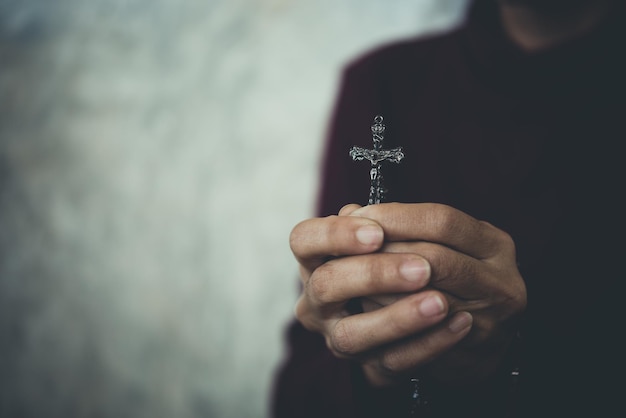 Seção média de uma pessoa segurando um crucifixo