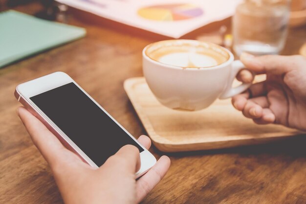 Foto seção média de uma pessoa segurando um telefone móvel na mesa