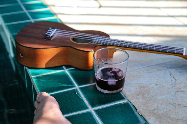 Foto seção média de uma pessoa segurando uma guitarra na piscina