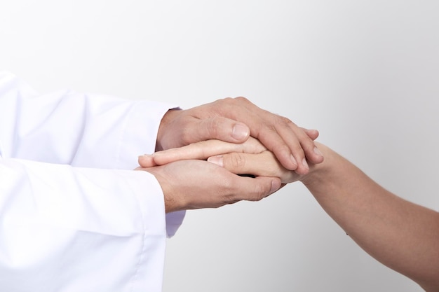 Seção média do médico segurando a mão do paciente contra um fundo cinzento