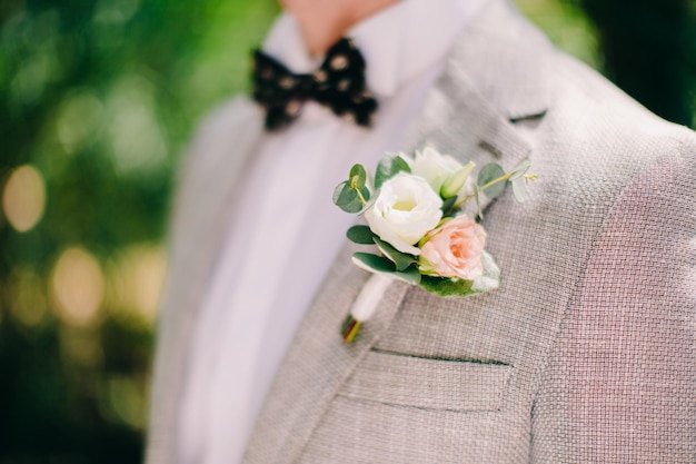Seção média do noivo vestindo boutonniere em terno