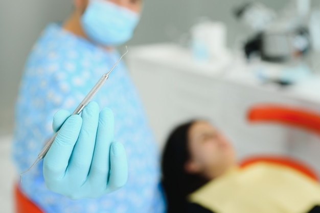 Seção mediana de dentista ajustando o avental em paciente do sexo feminino antes do tratamento na clínica