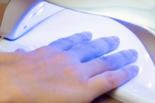 Foto secar as unhas após a aplicação de verniz em um secador ultravioleta especial