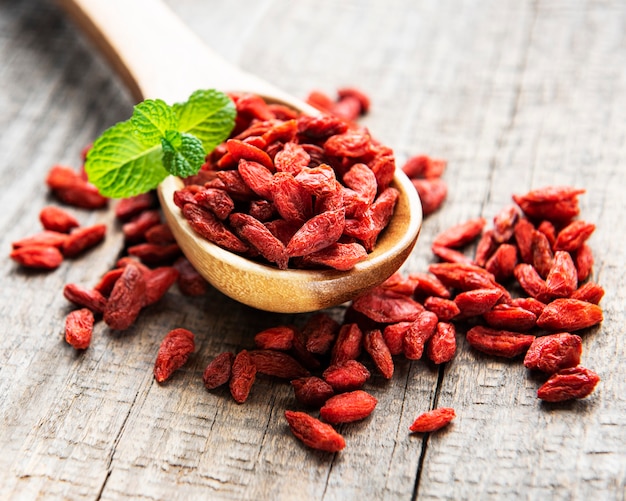 Secar las bayas de goji rojo para una dieta saludable en una superficie de madera vieja