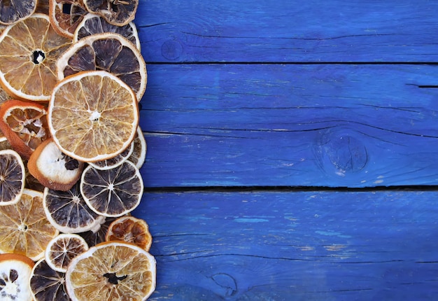 Secar rodajas de naranja y pomelo. Chips de fruta sobre fondo de tablas de madera azul envejecido.