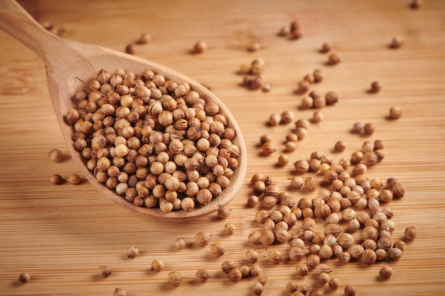 Secar las semillas de cilantro en una cuchara sobre una mesa de madera. De cerca, vista de enfoque selectivo.