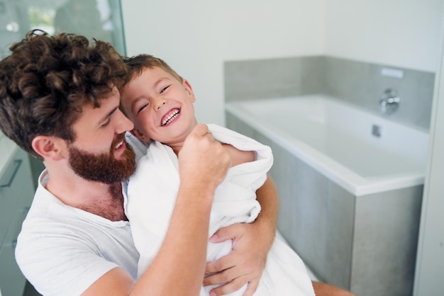 Secarte es el mejor momento para hacerte cosquillas Captura recortada de un joven y apuesto padre secando a su adorable hijito después de un baño en el baño de casa