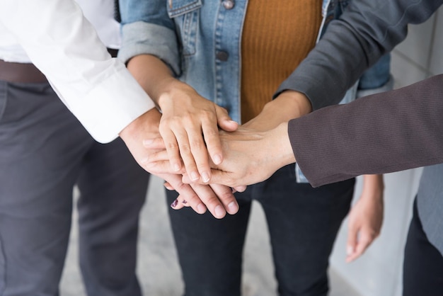 Secção média de colegas de negócios empilhando as mãos