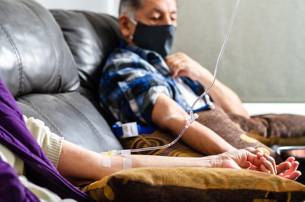 Secção média de homem e mulher com gotejamento intravenoso à mão no hospital
