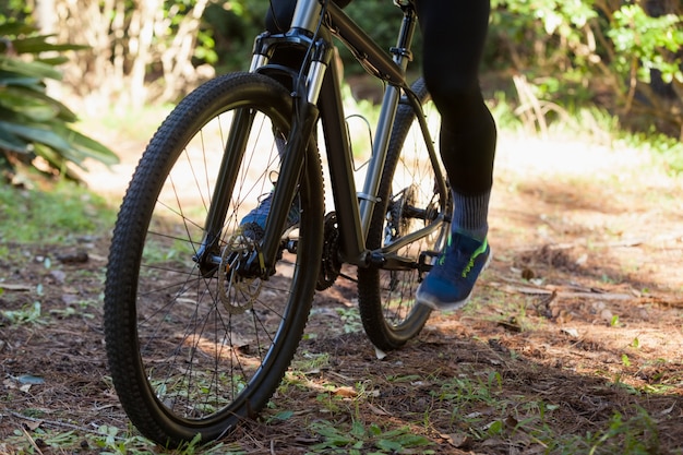 Sección baja del ciclista de montaña masculino montando bicicleta