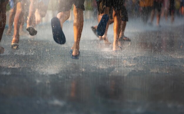 Sección baja de la gente en la carretera húmeda en la temporada de lluvias