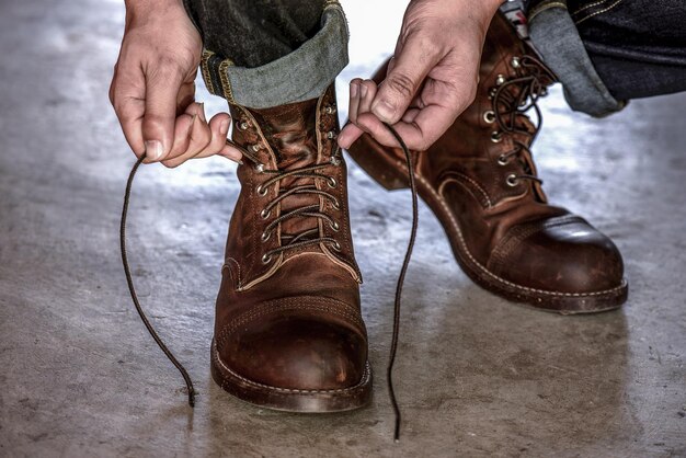 Sección baja de un hombre atando el cordón de los zapatos