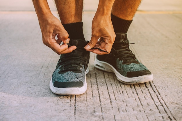 Foto sección baja de un hombre atando el cordón de los zapatos