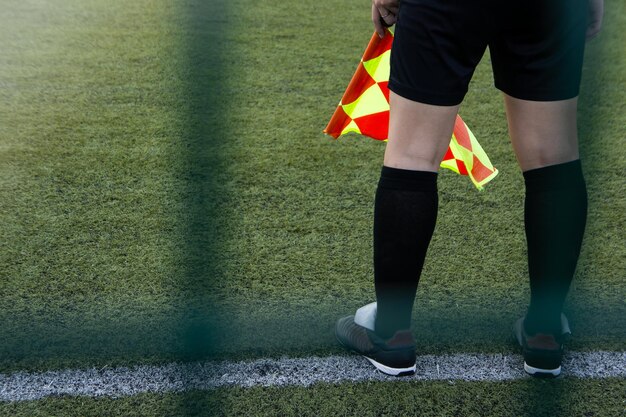 Sección baja de un hombre con una bandera de pie en un campo de fútbol