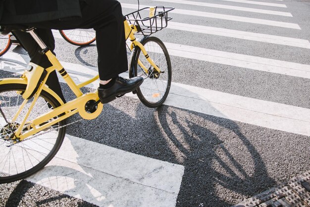 Foto sección baja de un hombre con una bicicleta cruzando la carretera