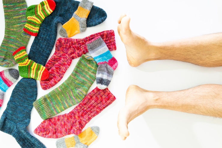 Foto sección baja del hombre por calcetines multicolores contra fondo blanco