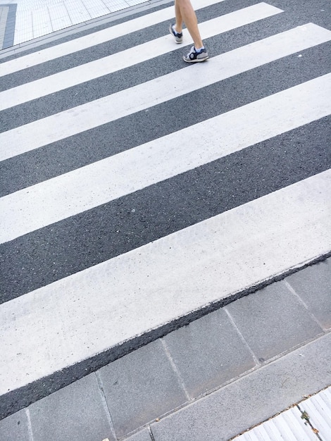 Foto sección baja de un hombre caminando por un cruce peatonal en la ciudad