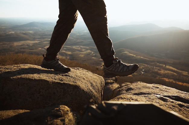 Sección baja de un hombre caminando sobre rocas contra las montañas