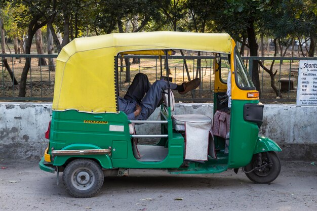 Foto sección baja de un hombre descansando en un rickshaw contra el parque