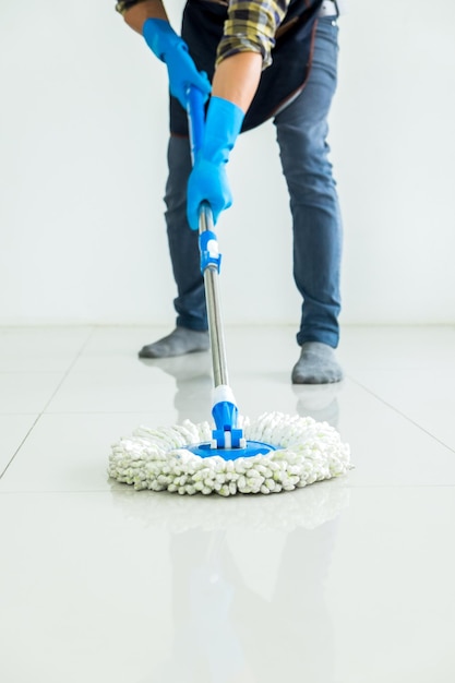 Foto sección baja del hombre limpiando el piso de baldosas en casa
