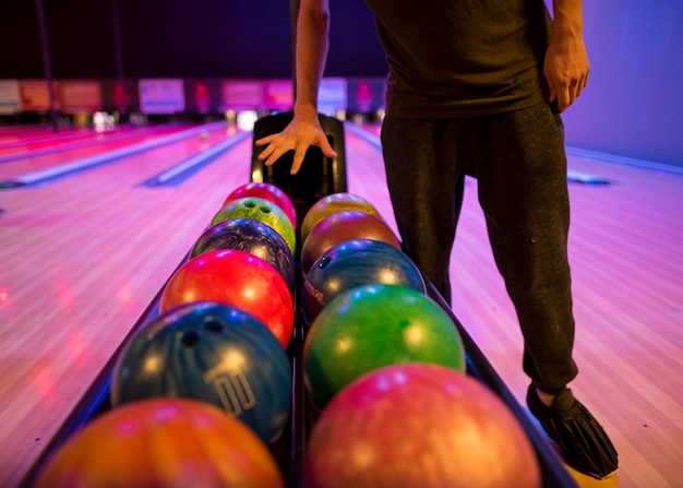 Foto sección baja de hombre con muchas bolas de bolos