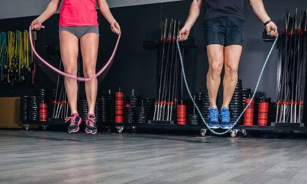 Foto sección baja de hombre y mujer saltando en el gimnasio