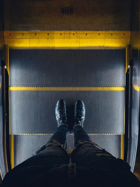 Foto sección baja de un hombre de pie en una escalera mecánica