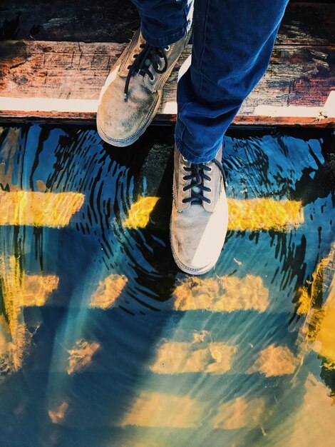 Foto sección baja de un hombre de pie en escalones sobre el lago