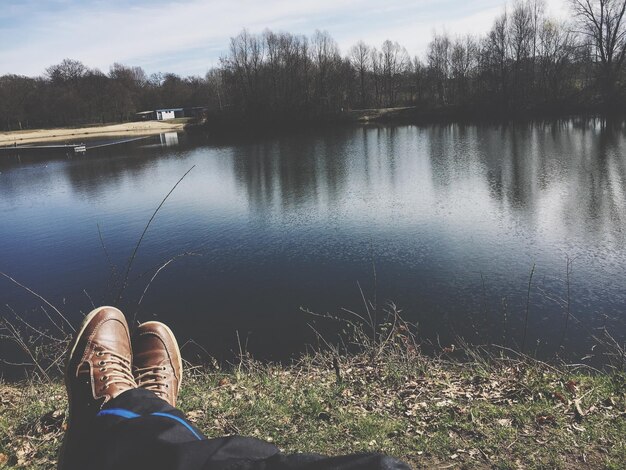 Foto sección baja de un hombre de pie junto al lago